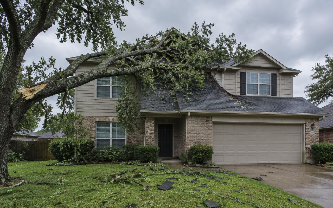 AI illustration: a large oak limb lying across the gray shingle roof of a two-story home, with torn shingle pieces on the lawn